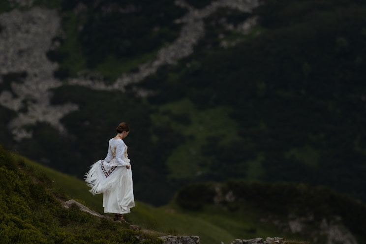 A woman in a white dress walking up a hill