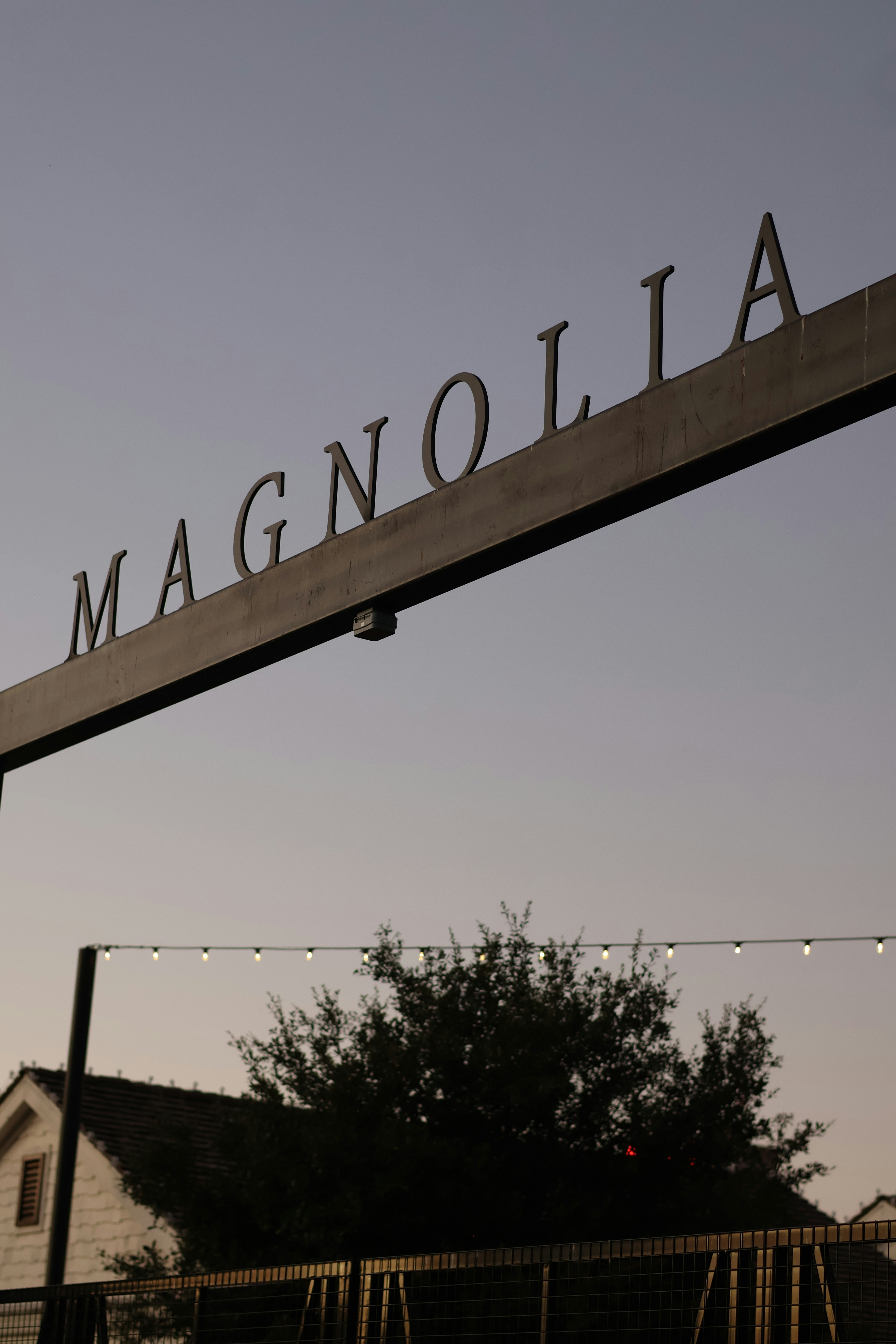 A street sign that reads magnanolia above a fence