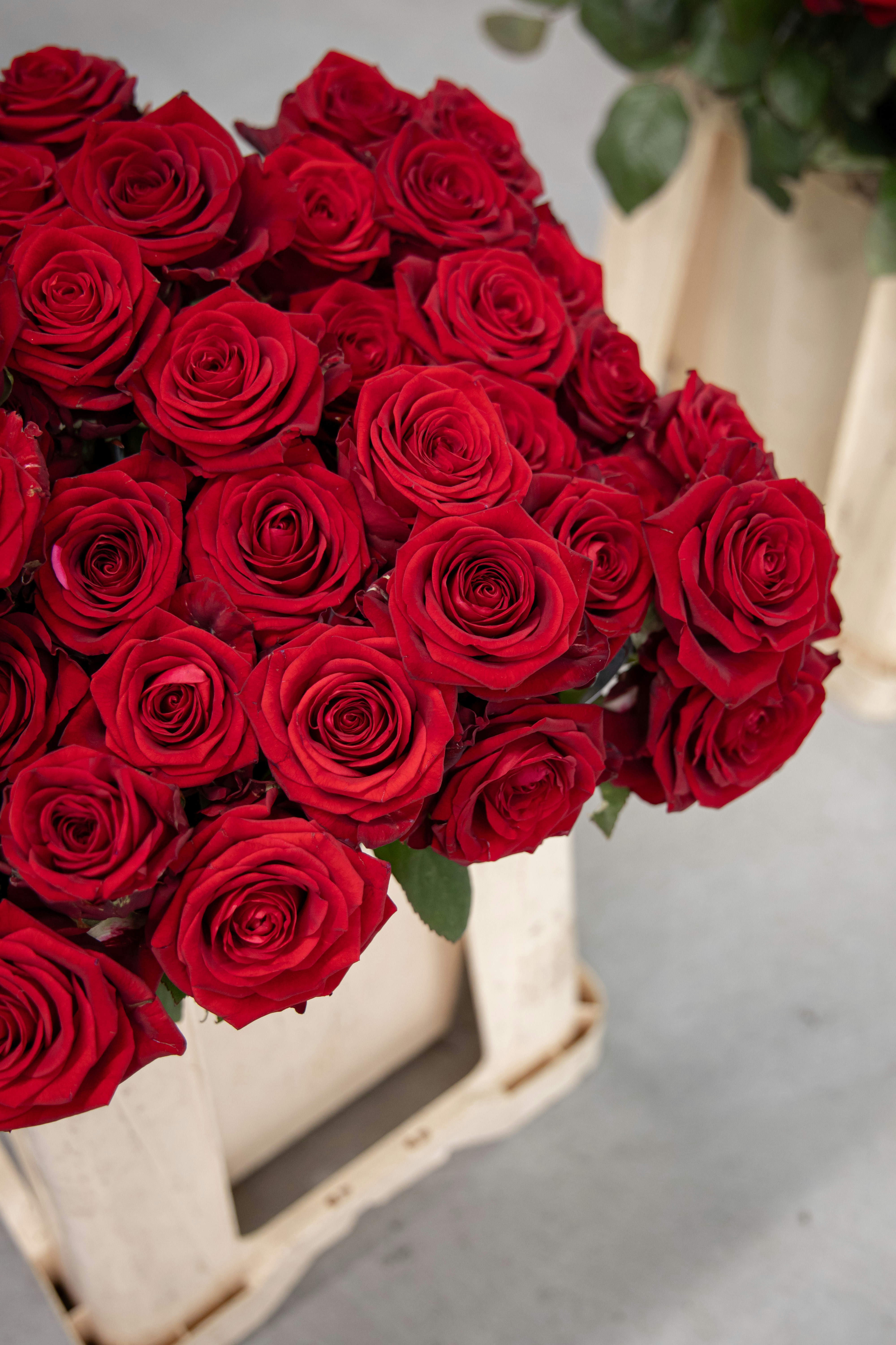 A large bouquet of red roses in a wooden crate