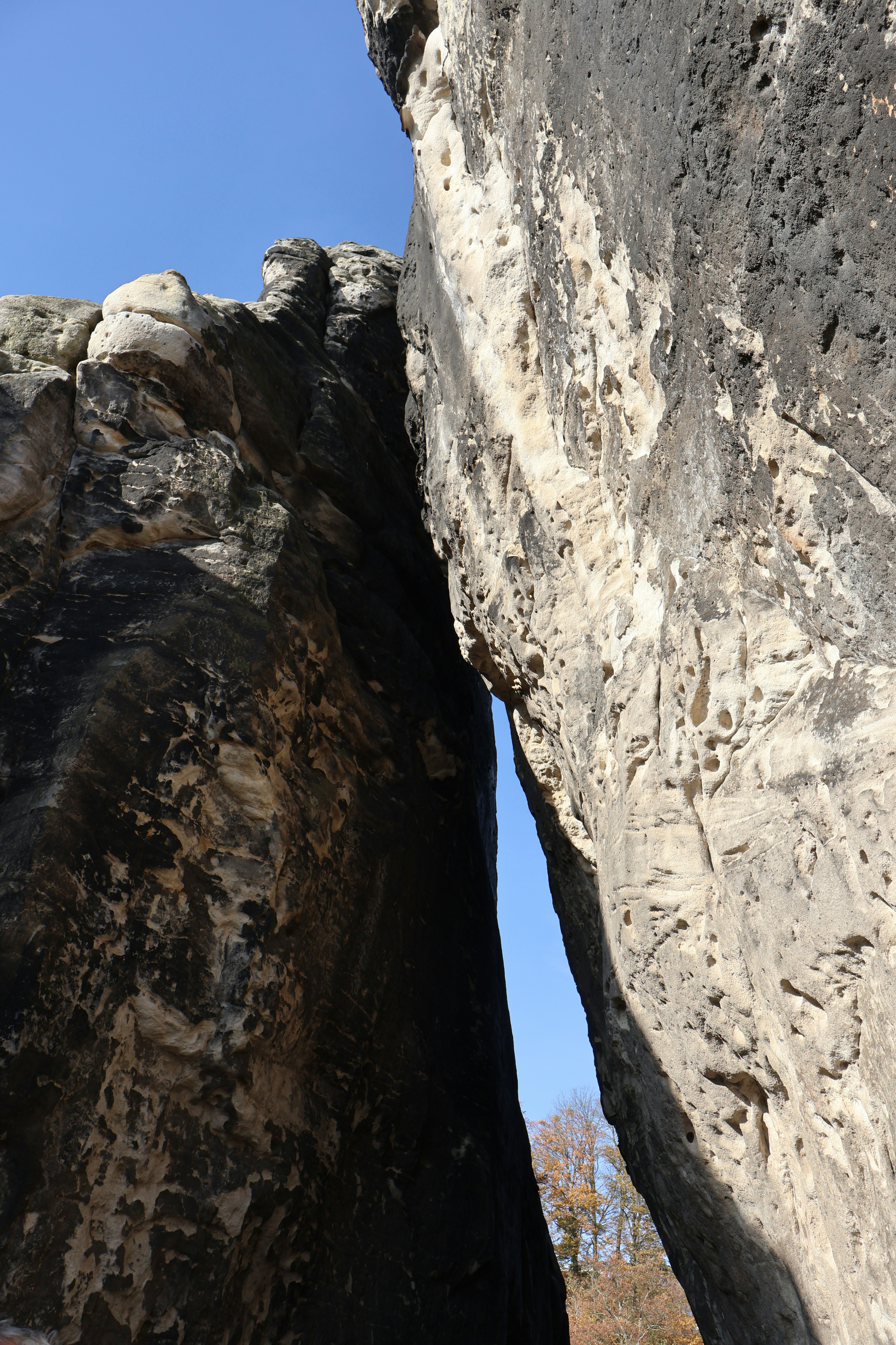 A person climbing up a large rock with a sky background