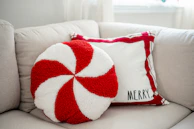 A red and white pillow sitting on top of a white couch