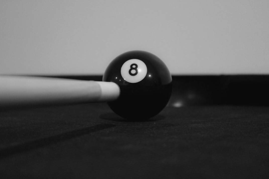A pool ball with a cue resting on it, 8ball
