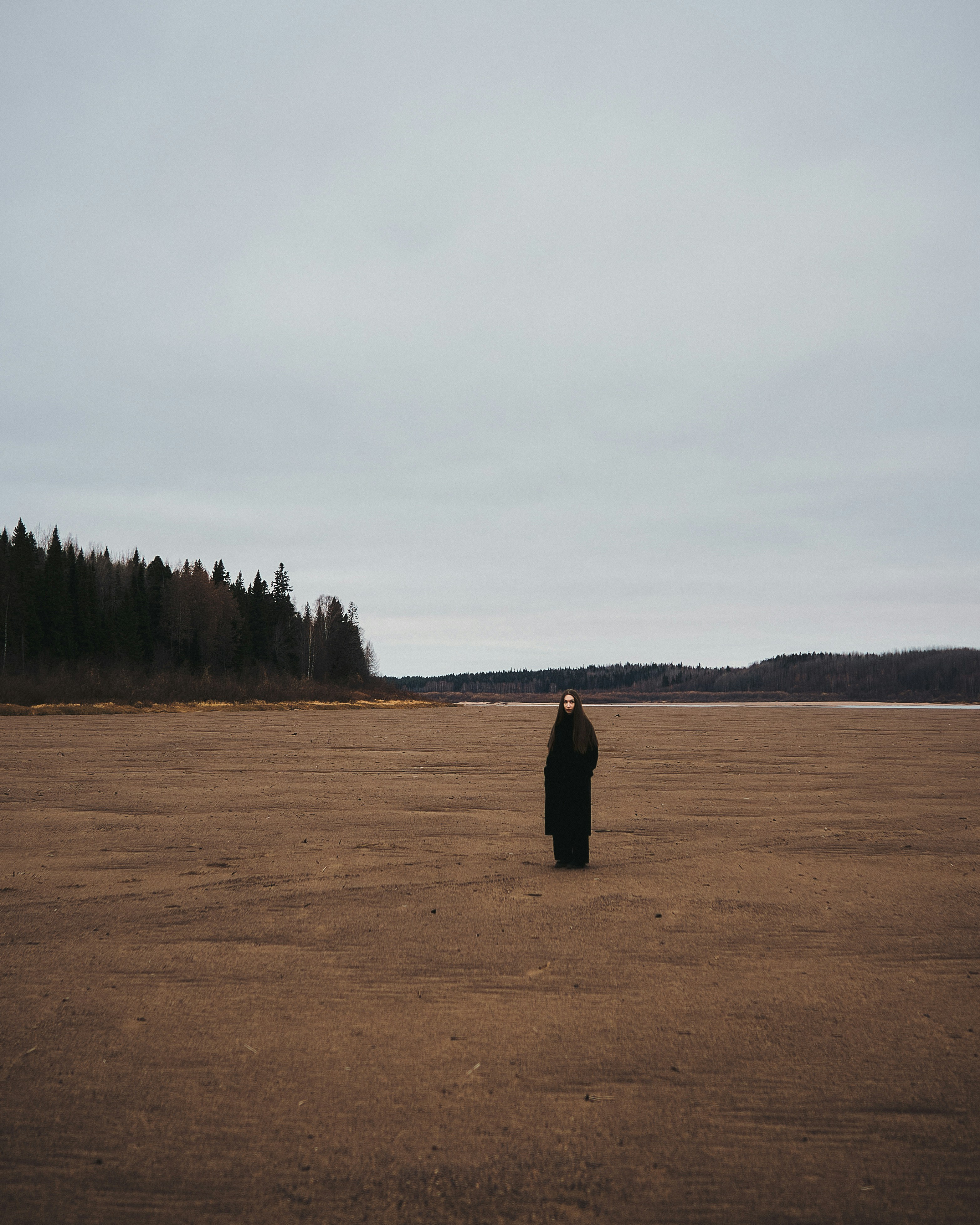 A person standing in a field with trees in the background