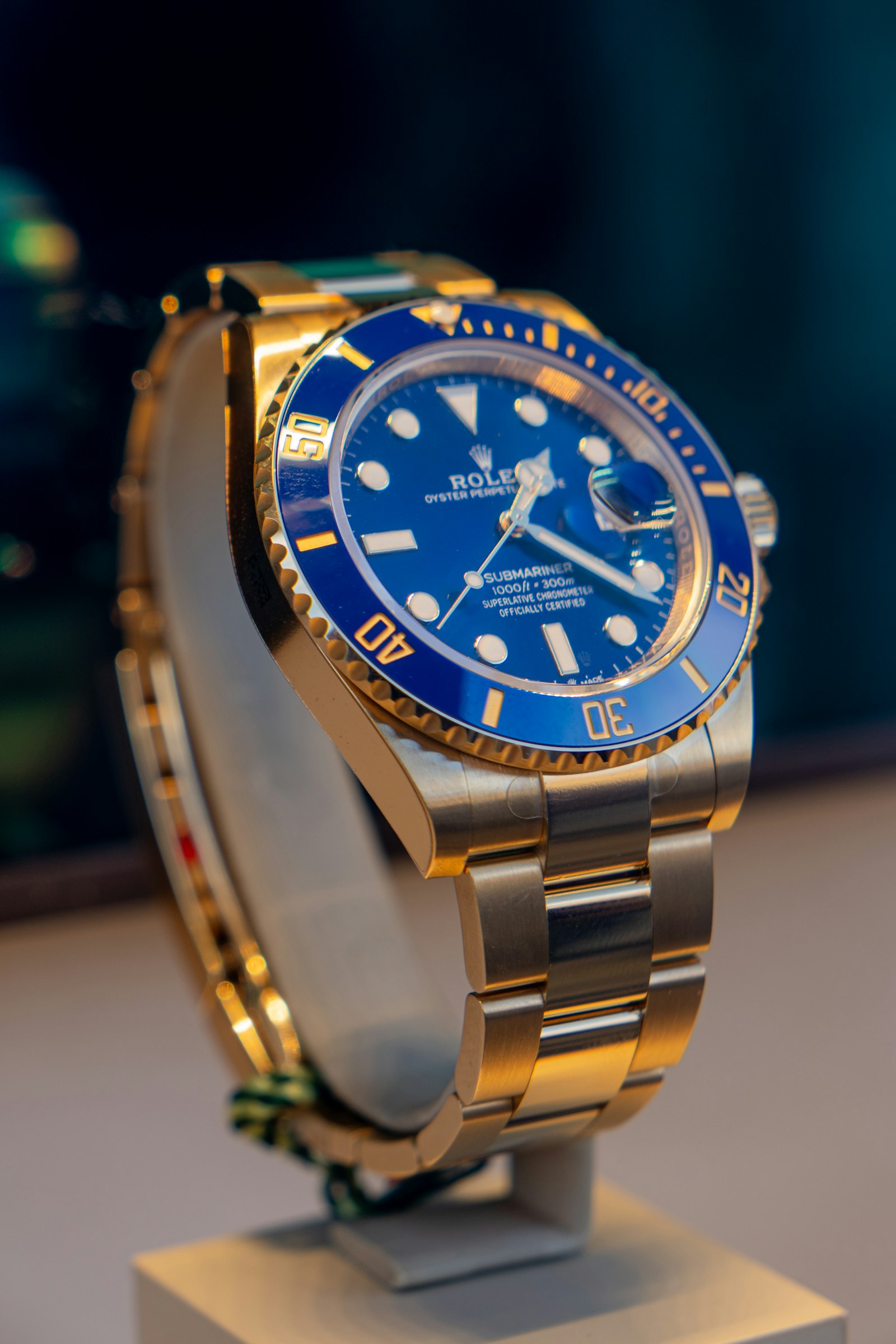 Blue and gold Rolex watch displayed on a stand