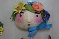 A wall hanging with a face and flowers on it