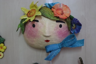 A wall hanging with a face and flowers on it