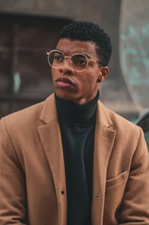 A man in a brown jacket and black turtle neck sweater
