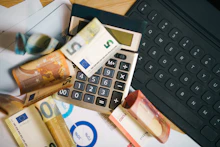 A calculator sitting on top of a pile of money