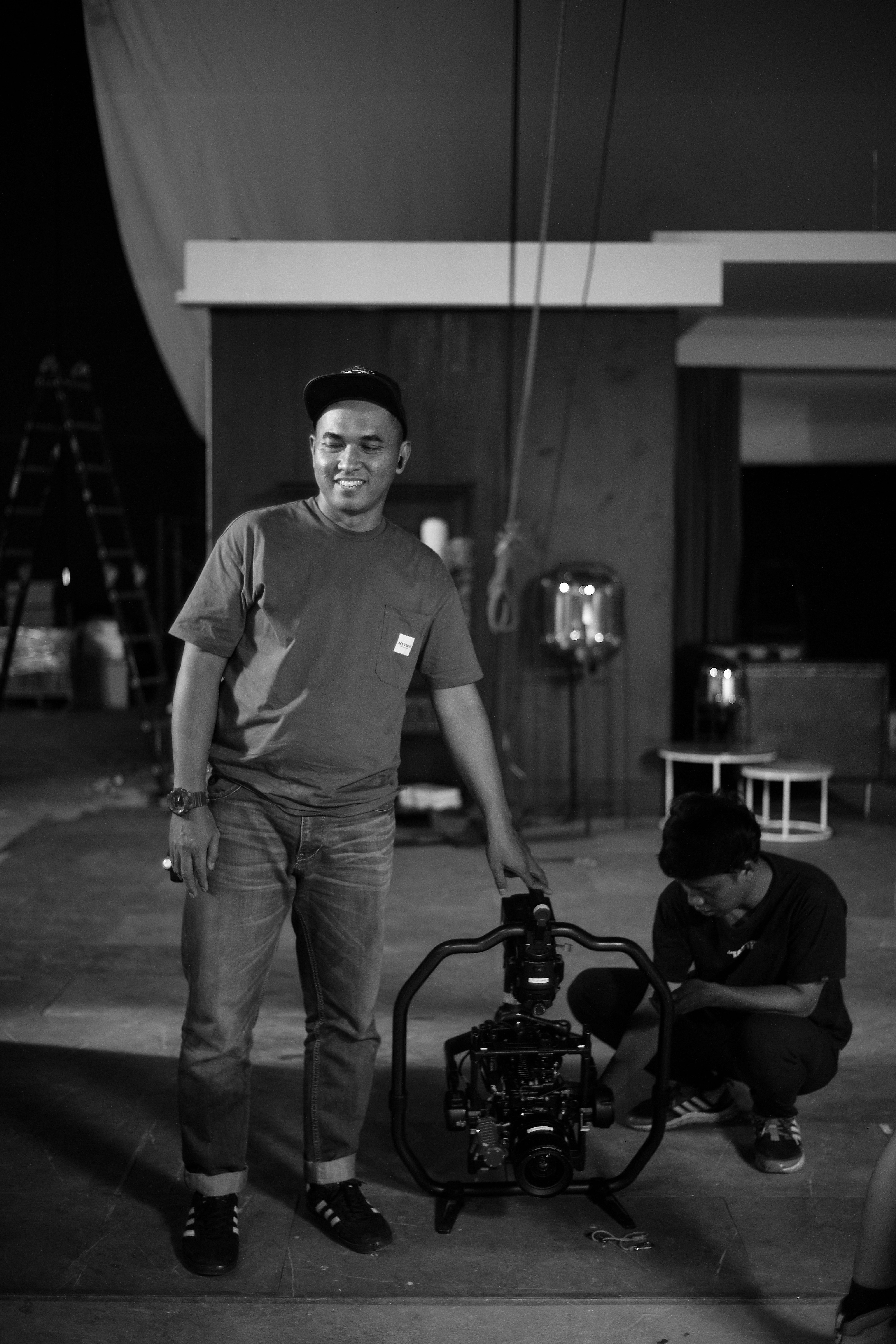 A black and white photo of a man standing next to a camera