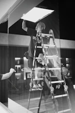 A man standing on top of a ladder next to a window