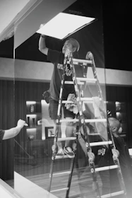 A man standing on top of a ladder next to a window