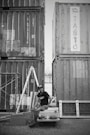 A man sitting on top of a car in front of shipping containers