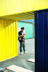 A man standing in front of a yellow and blue building
