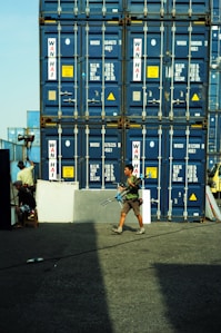 A man walking past a large stack of shipping containers