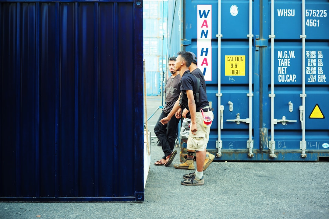 A couple of men standing next to a blue container,