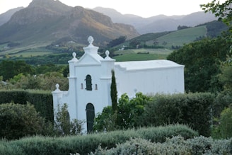 A white church surrounded by greenery and mountains