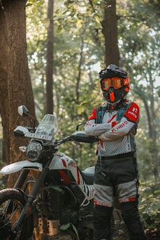 A man standing next to a motorcycle in the woods
