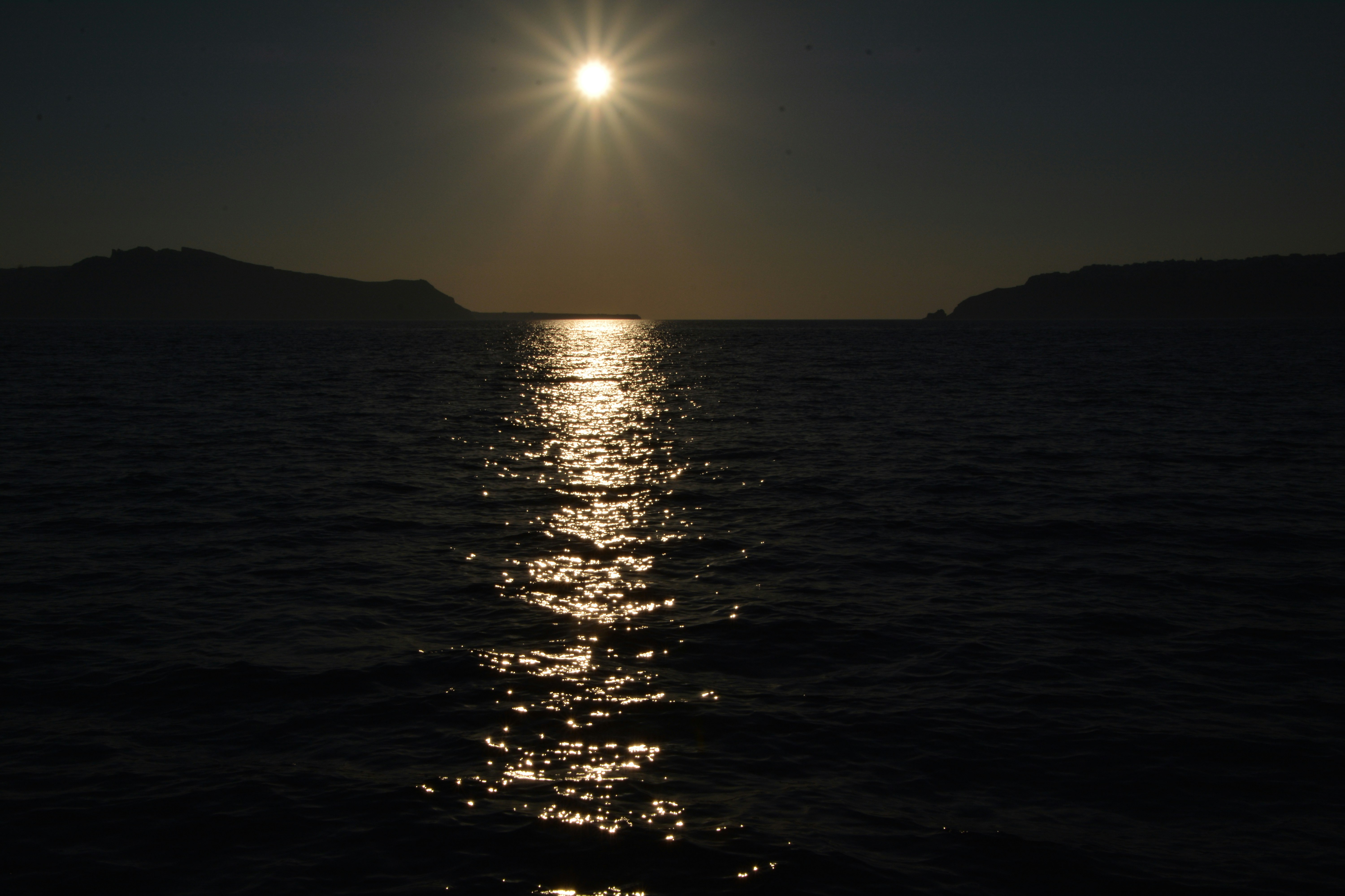 The sun is shining over the water at night