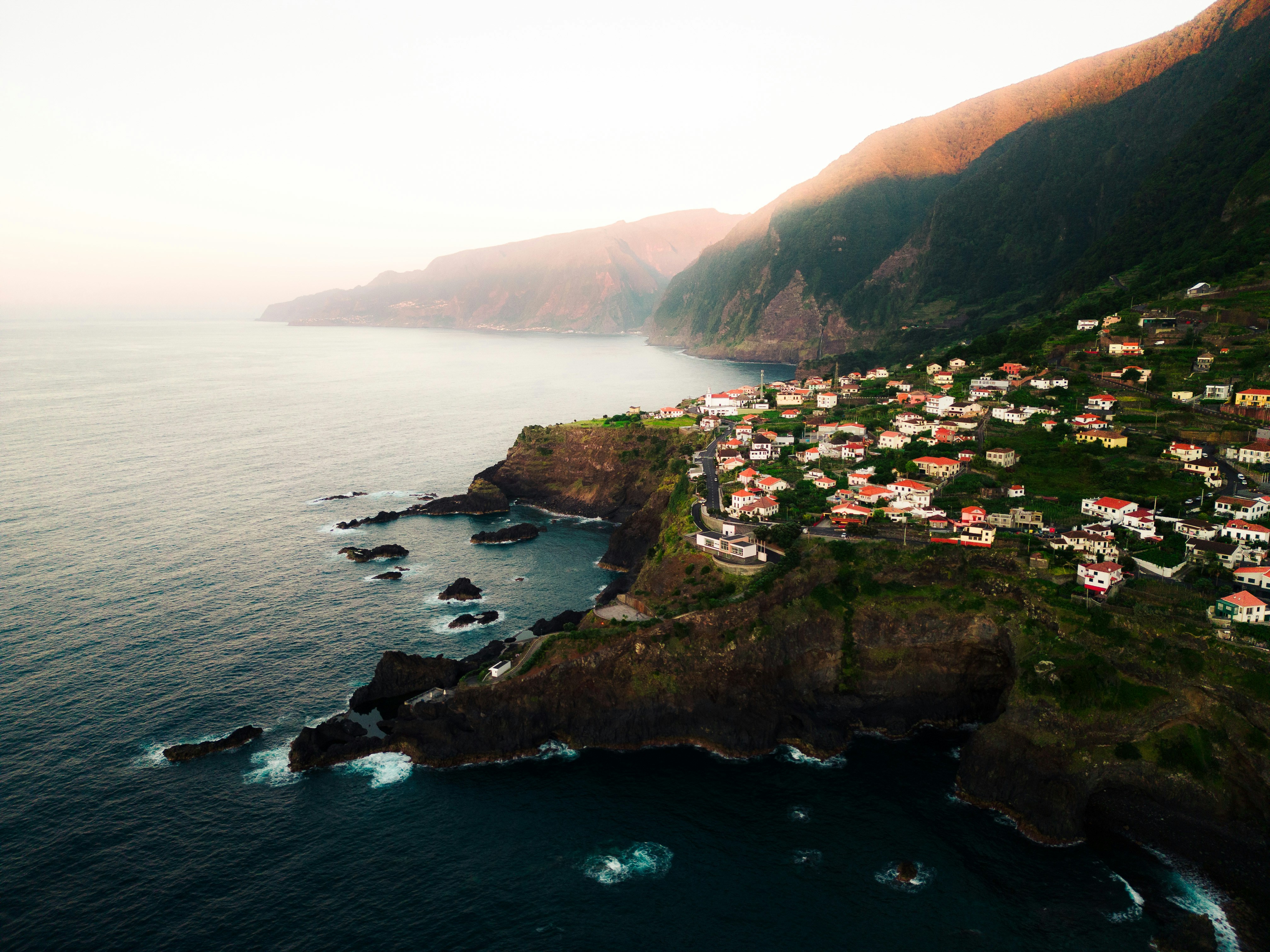 An aerial view of a village on a cliff overlooking the ocean