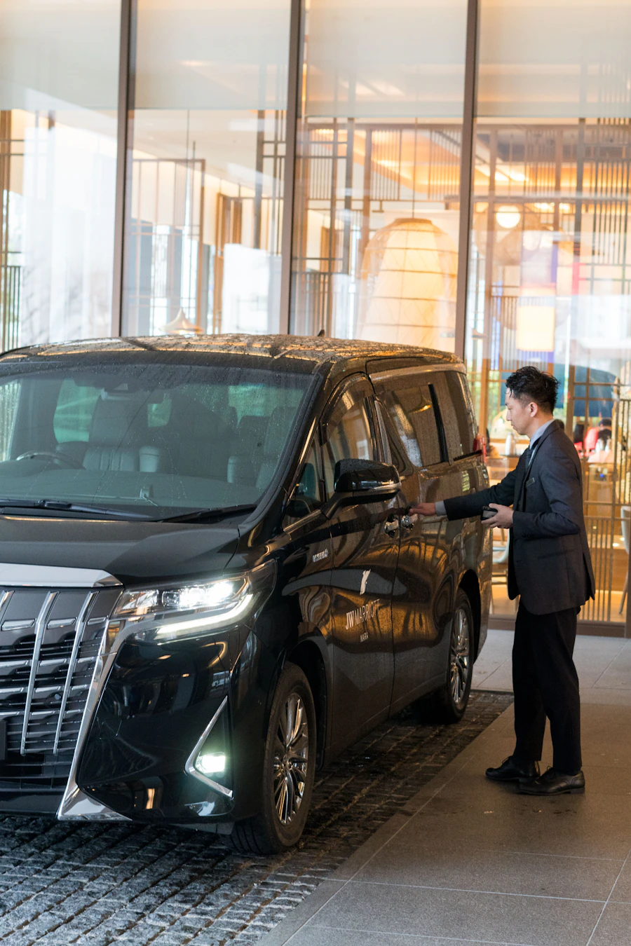 Chauffeur in pak naast een Taxi Jer voertuig