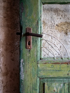 A green door with a rusted metal handle