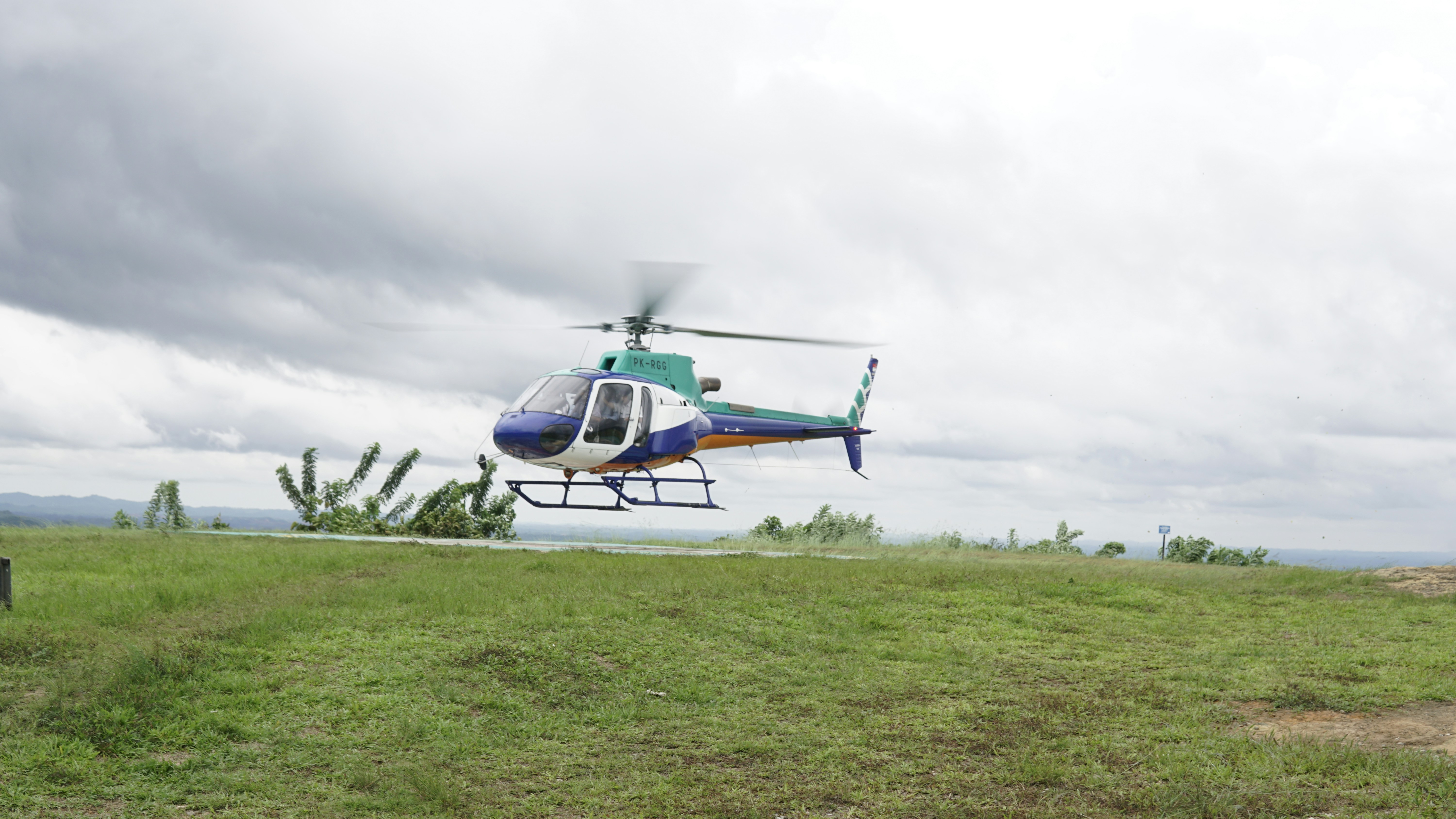 A helicopter flying over a lush green field