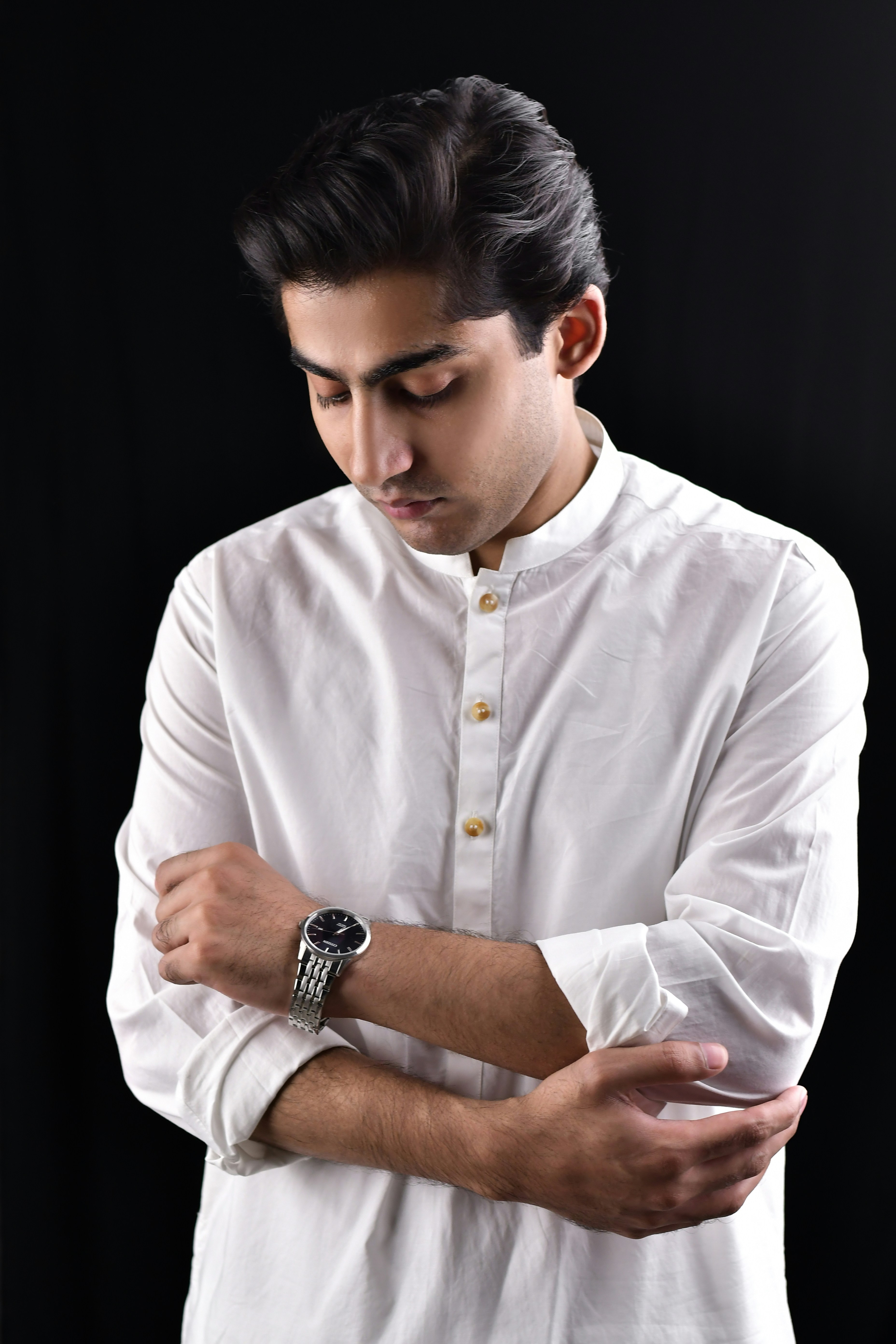 A man in a white shirt is holding his hands together