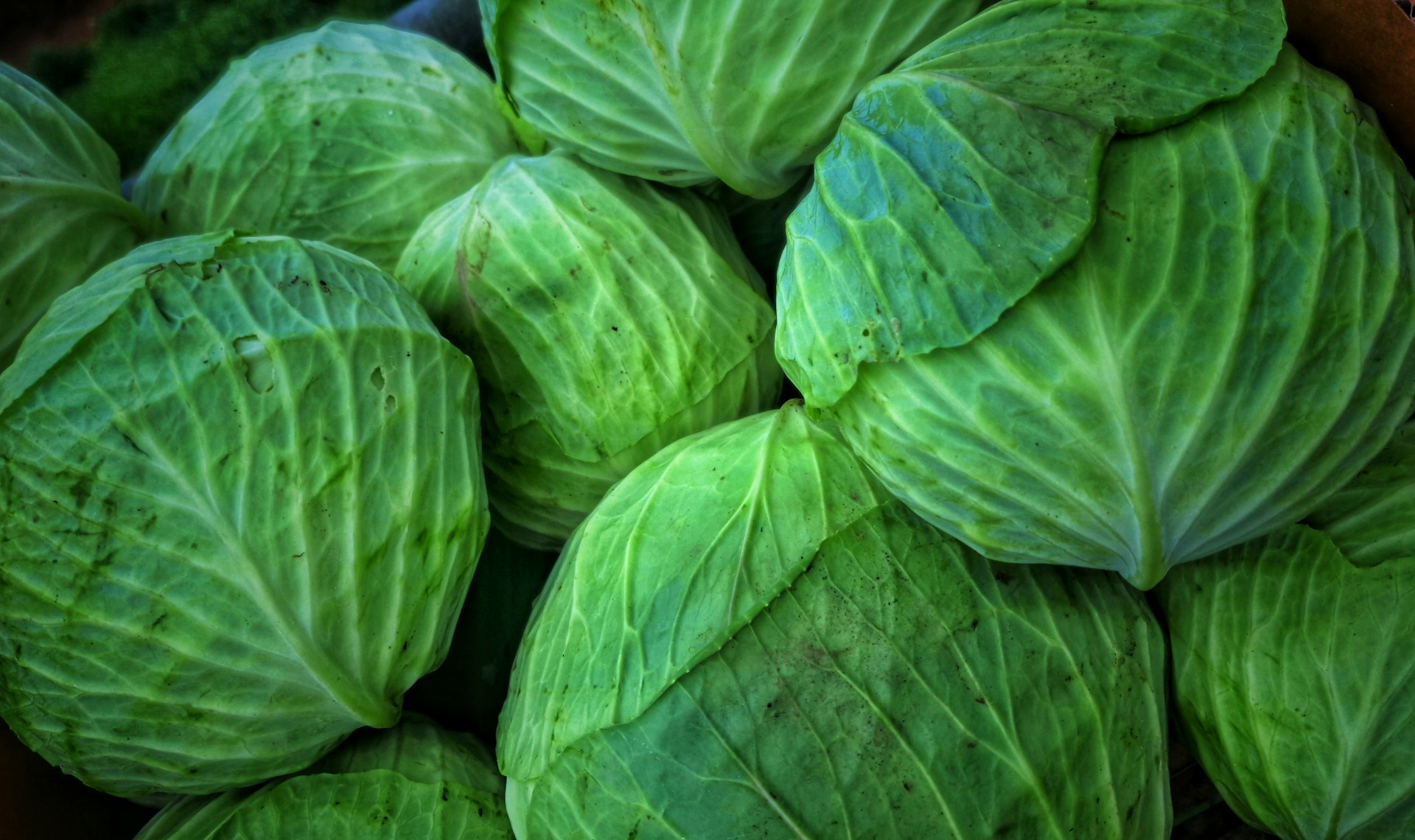 A basket full of green cabbages sitting on top of a table