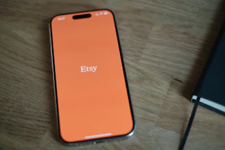 An orange cell phone sitting on top of a wooden table