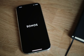 A black cell phone sitting on top of a wooden table