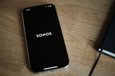 A black cell phone sitting on top of a wooden table