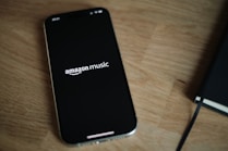 Amazon Music logo on a cell phone on top of a wooden table