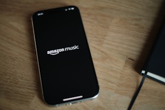 Amazon Music logo on a cell phone on top of a wooden table