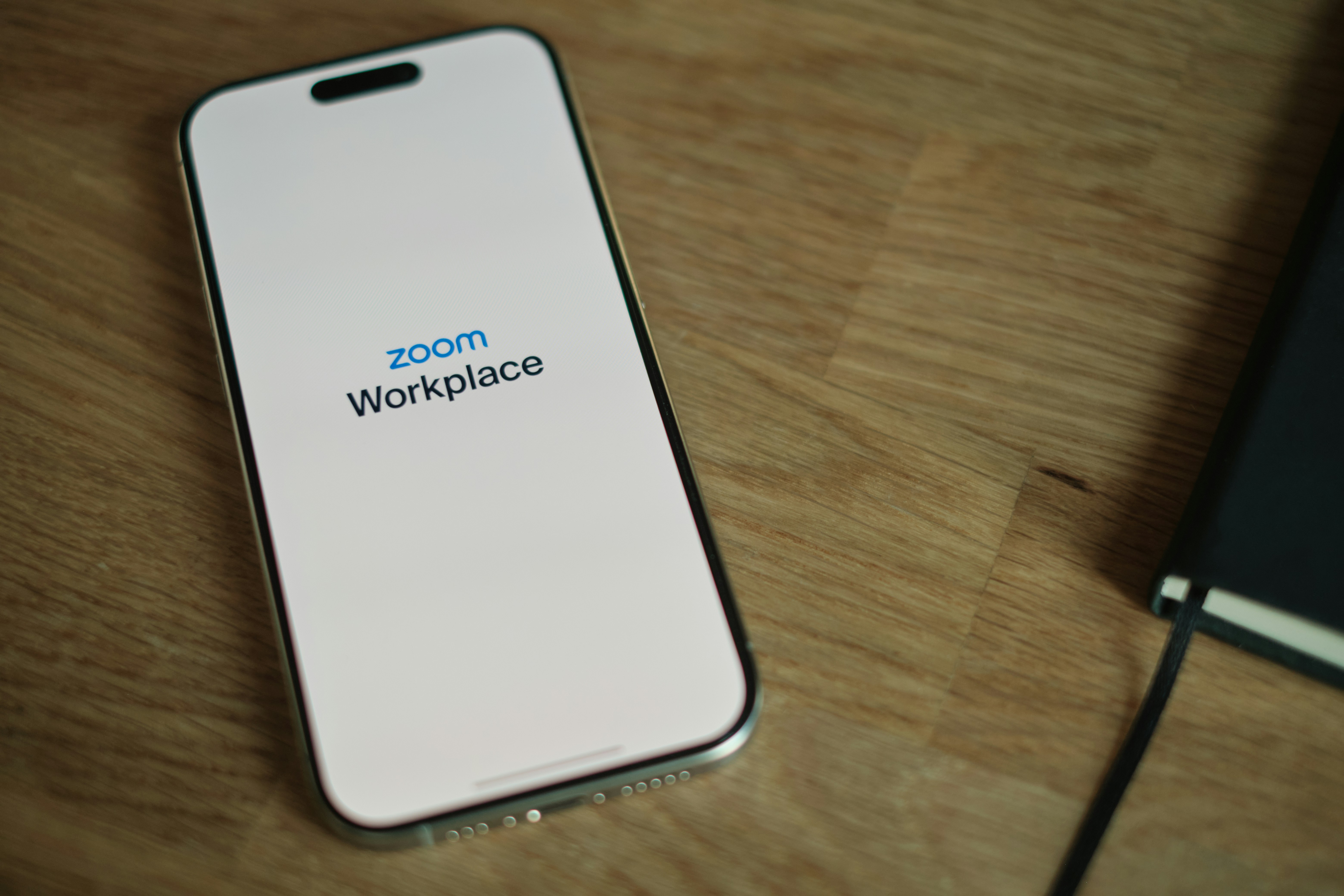  A close-up of a smartphone screen showing a complex yet organized digital workflow, possibly with charts or project management tools, with a blurred office desk in the background.