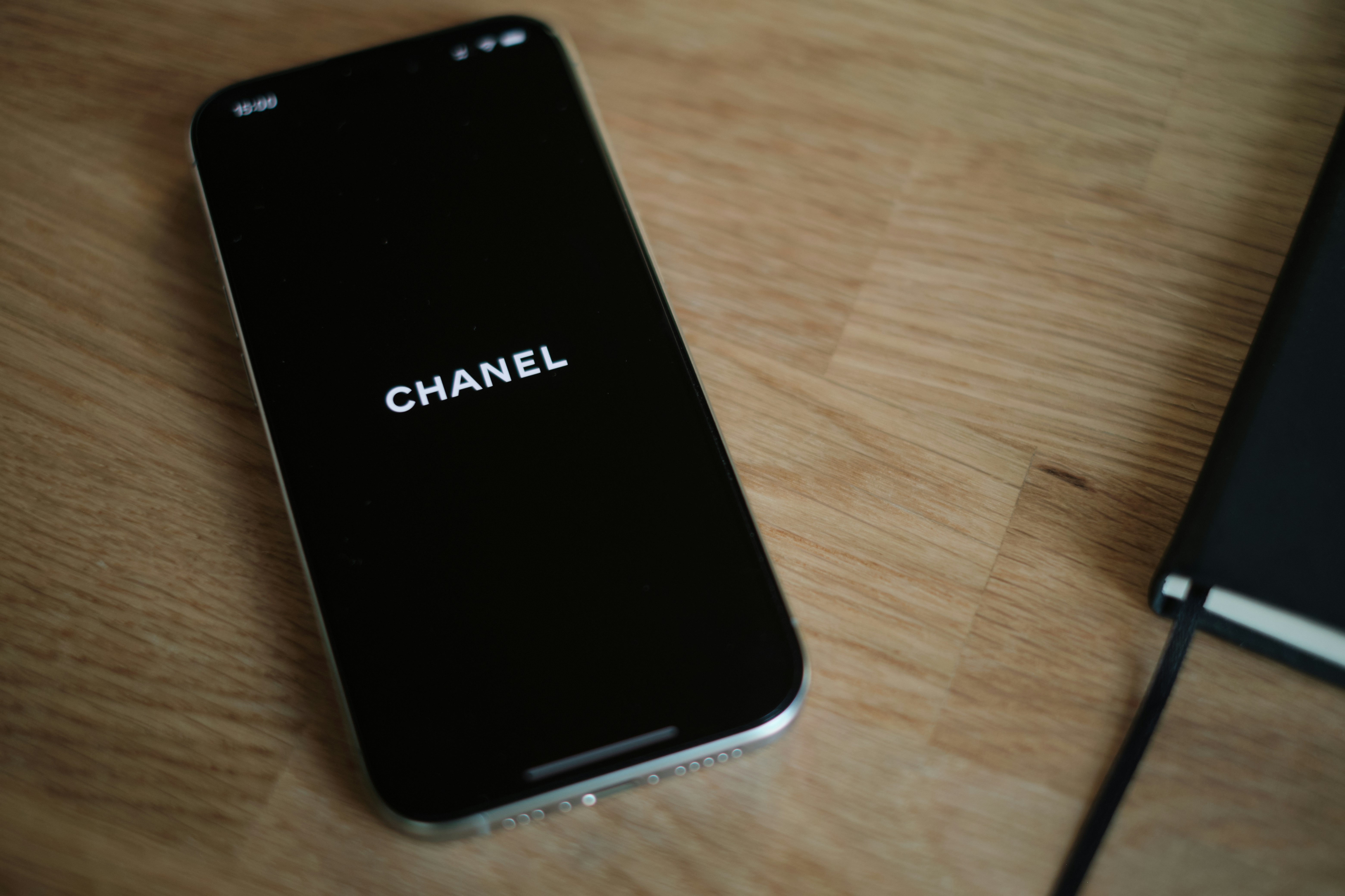 A black cell phone sitting on top of a wooden table
