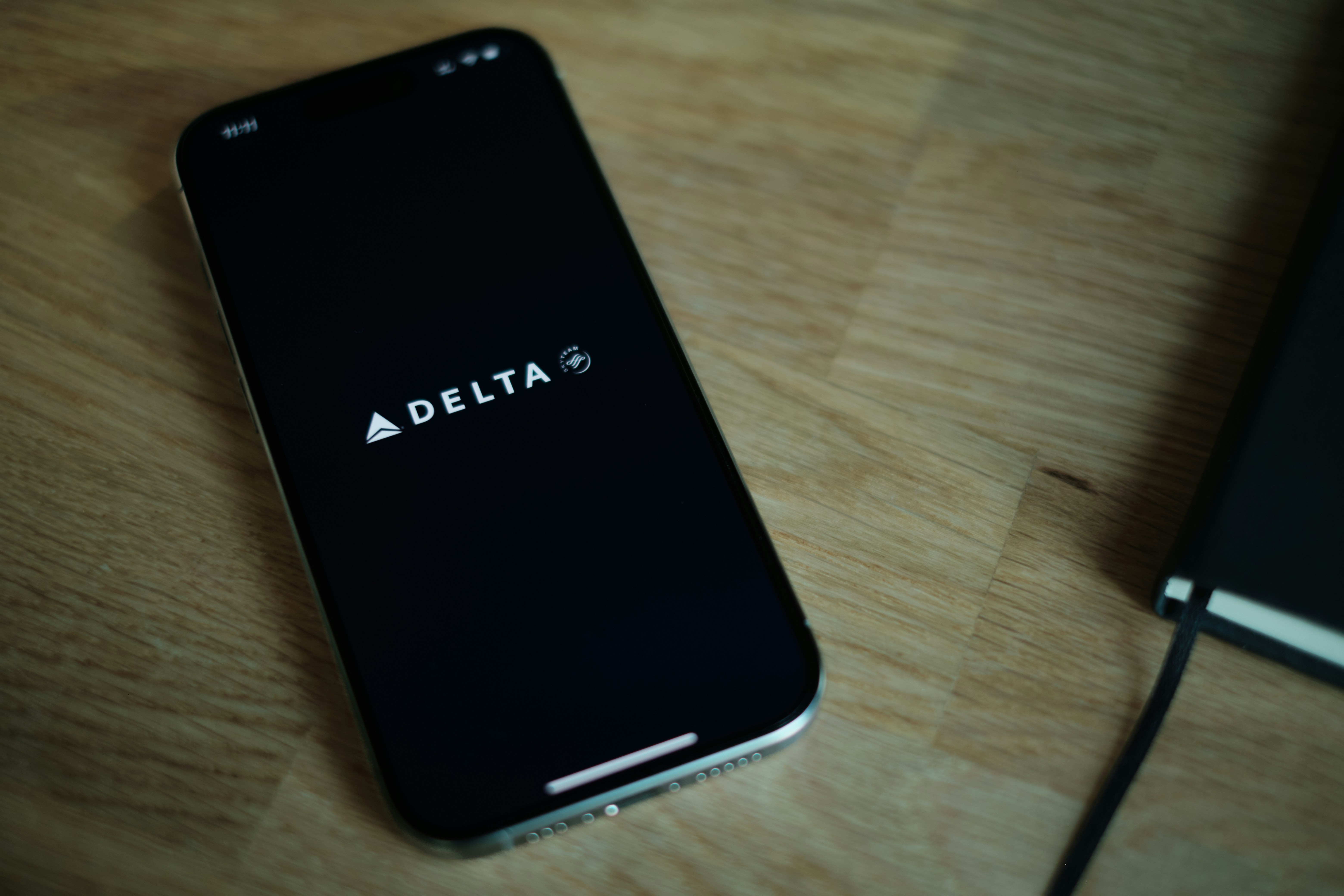 Un teléfono celular negro encima de una mesa de madera