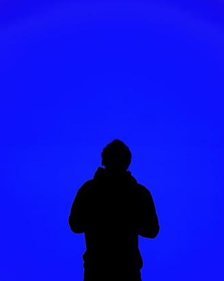 A silhouette of a person standing in front of a blue sky