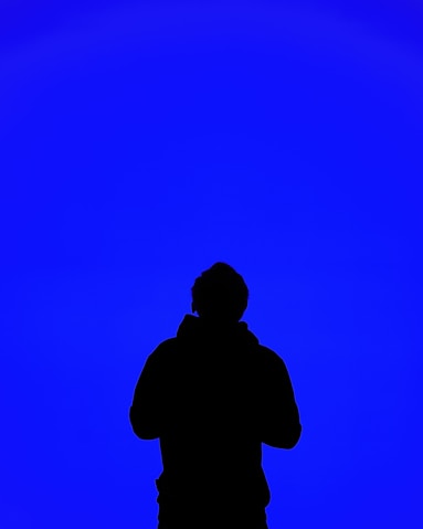 A silhouette of a person standing in front of a blue sky