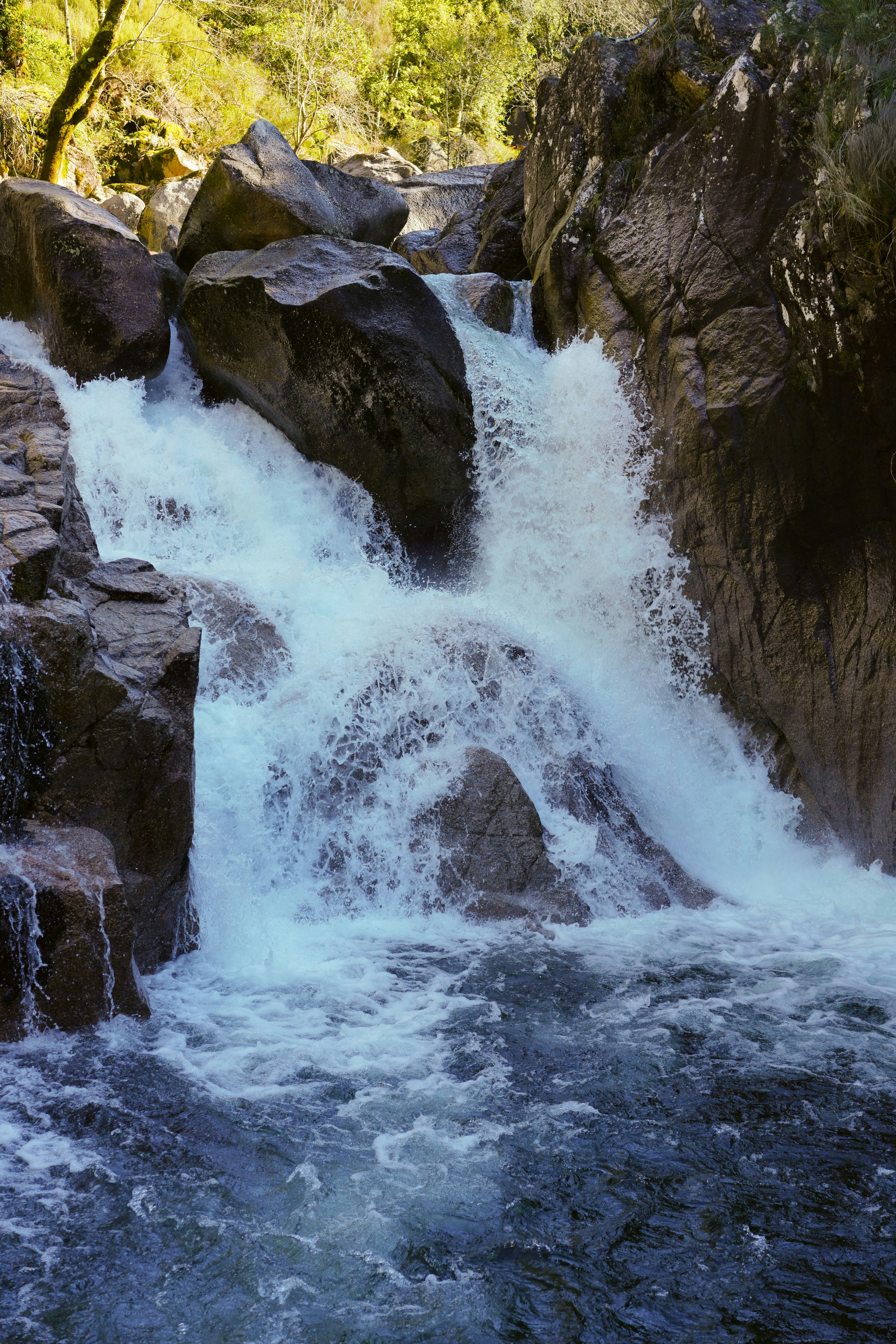 A man standing on a rock next to a waterfall