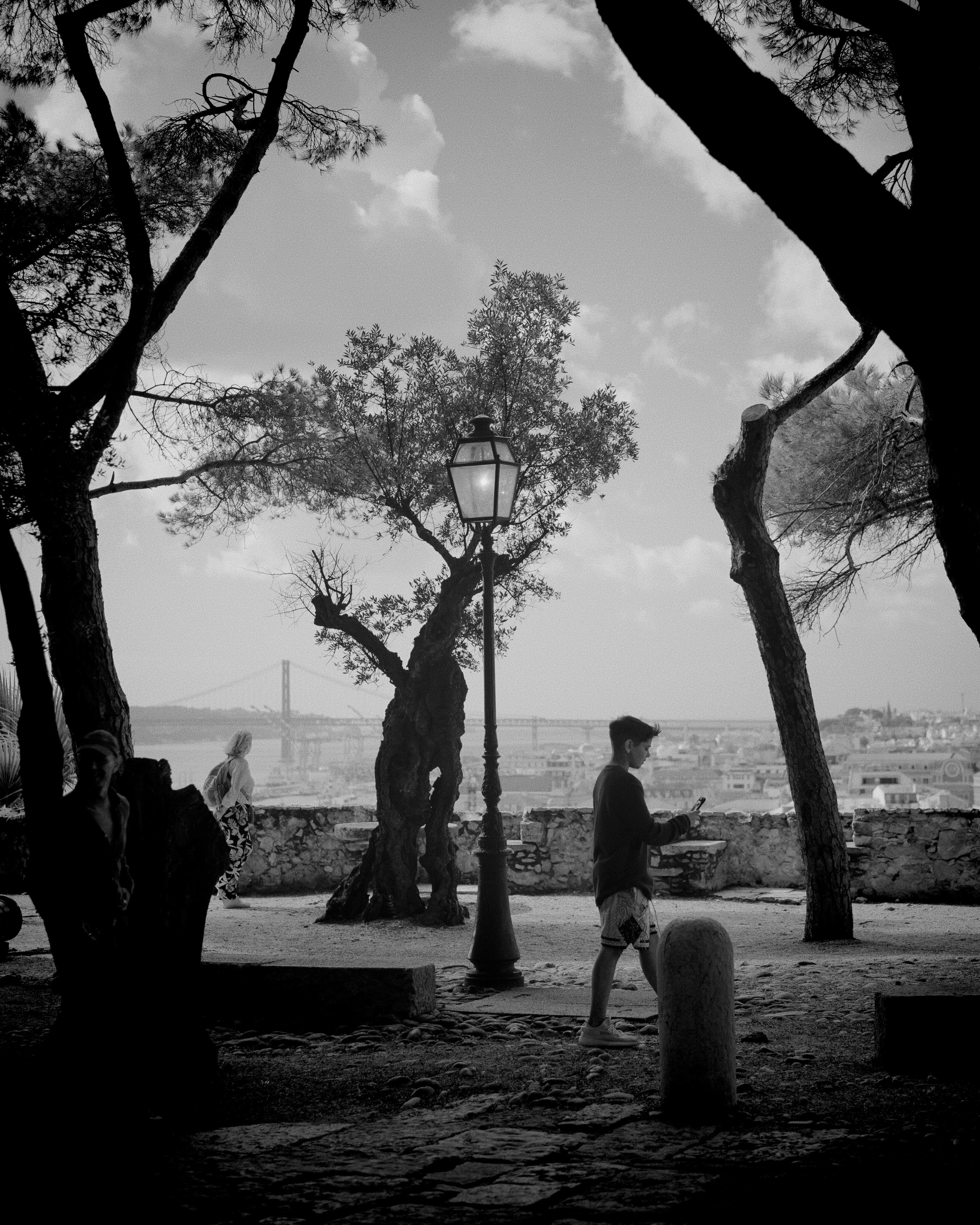 A black and white photo of a man walking through a park