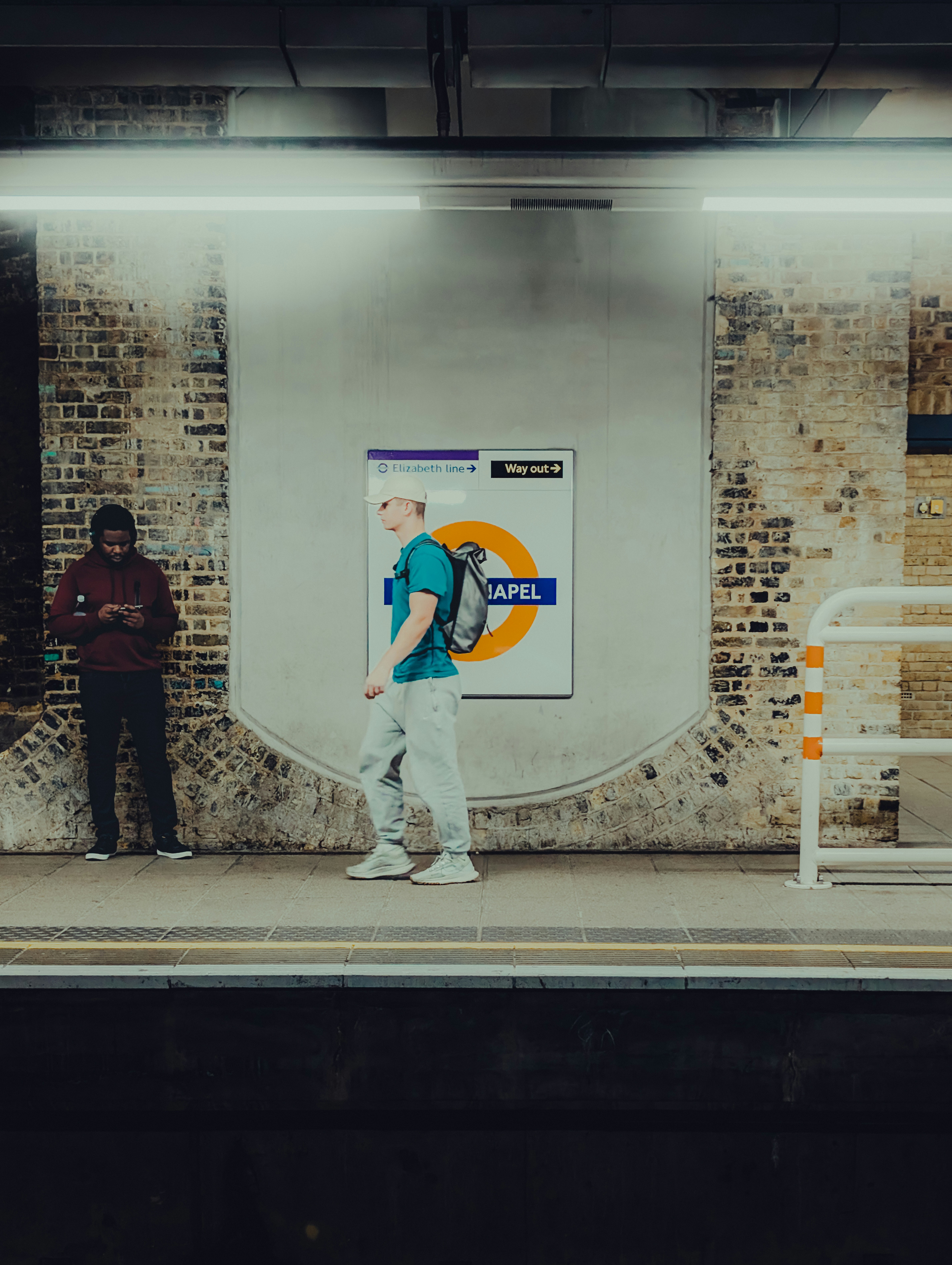 A man standing on a train platform next to a white bench