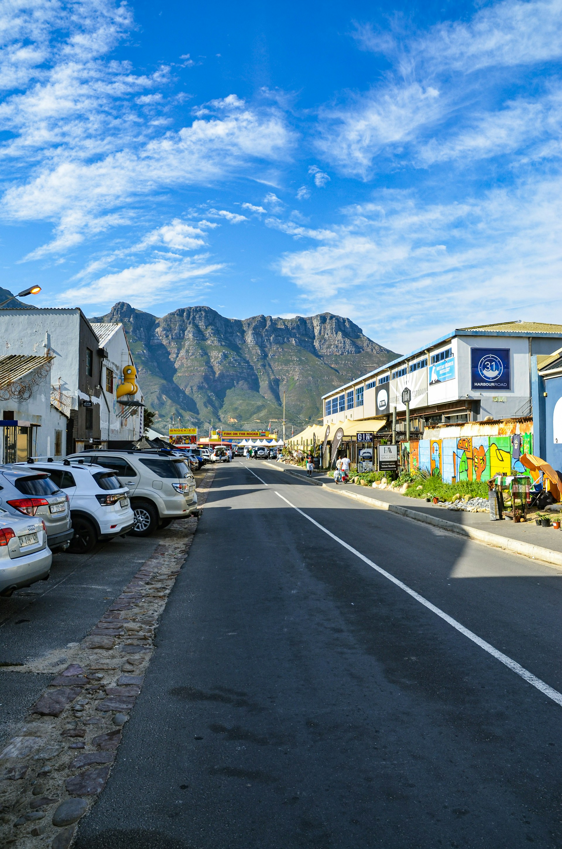 A street lined with parked cars next to tall mountains