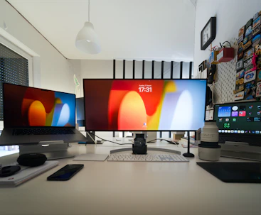 Three computer monitors sitting on top of a desk