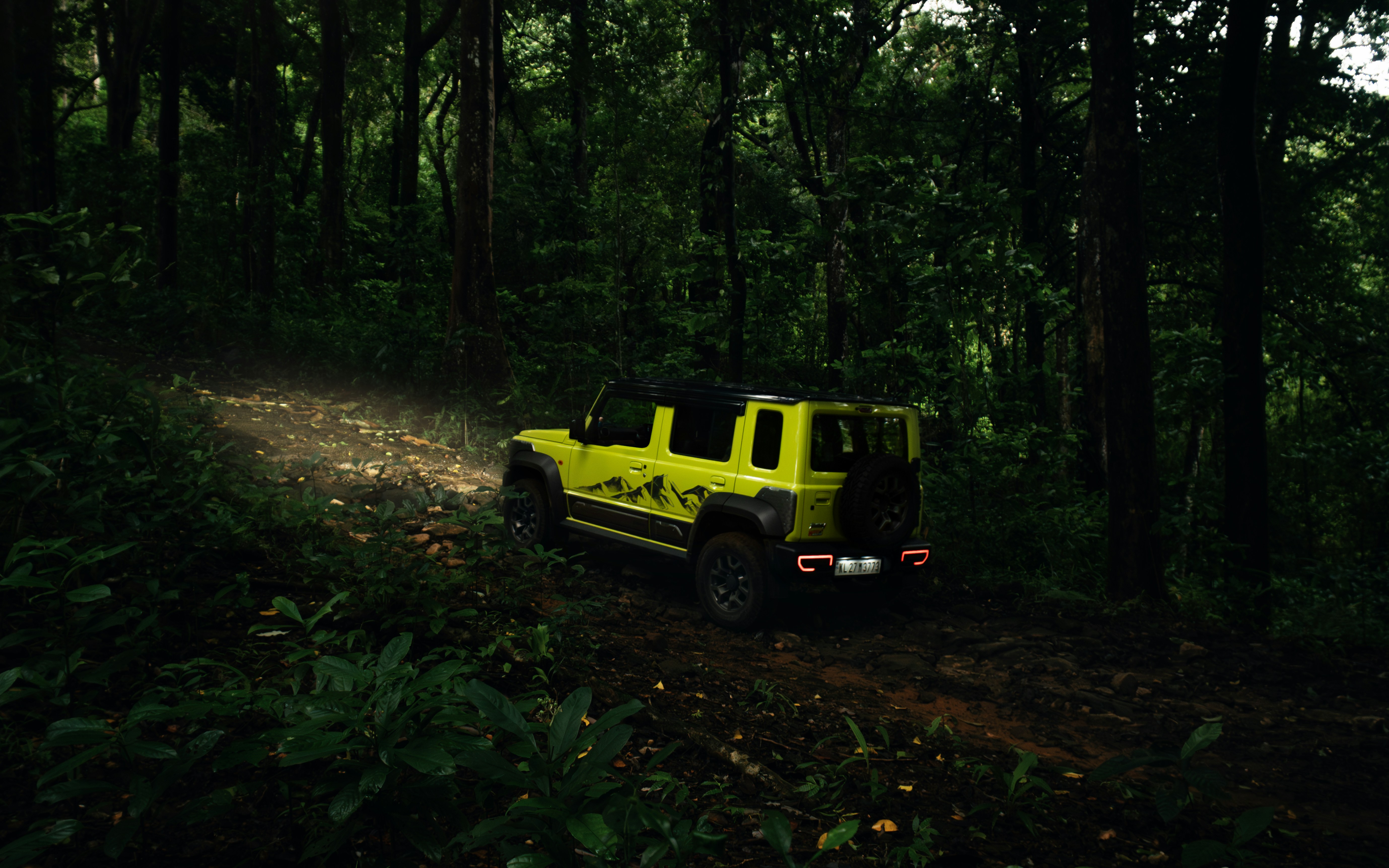 Une jeep jaune traversant une forêt remplie d’arbres