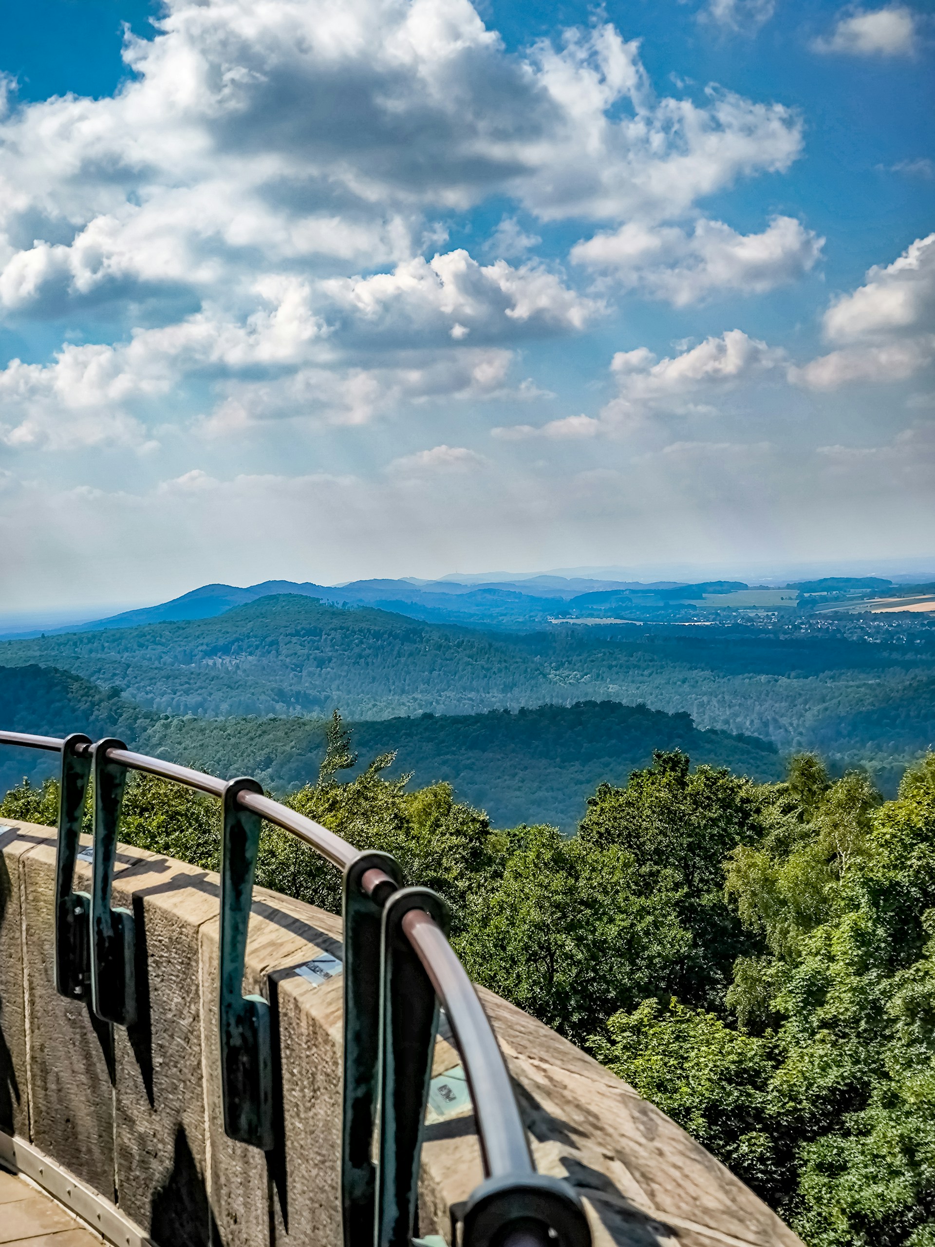 A man standing on top of a mountain next to a railing