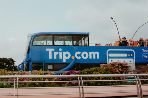 A blue double decker bus driving down a street
