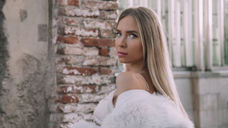 A woman with long blonde hair standing in front of a brick wall