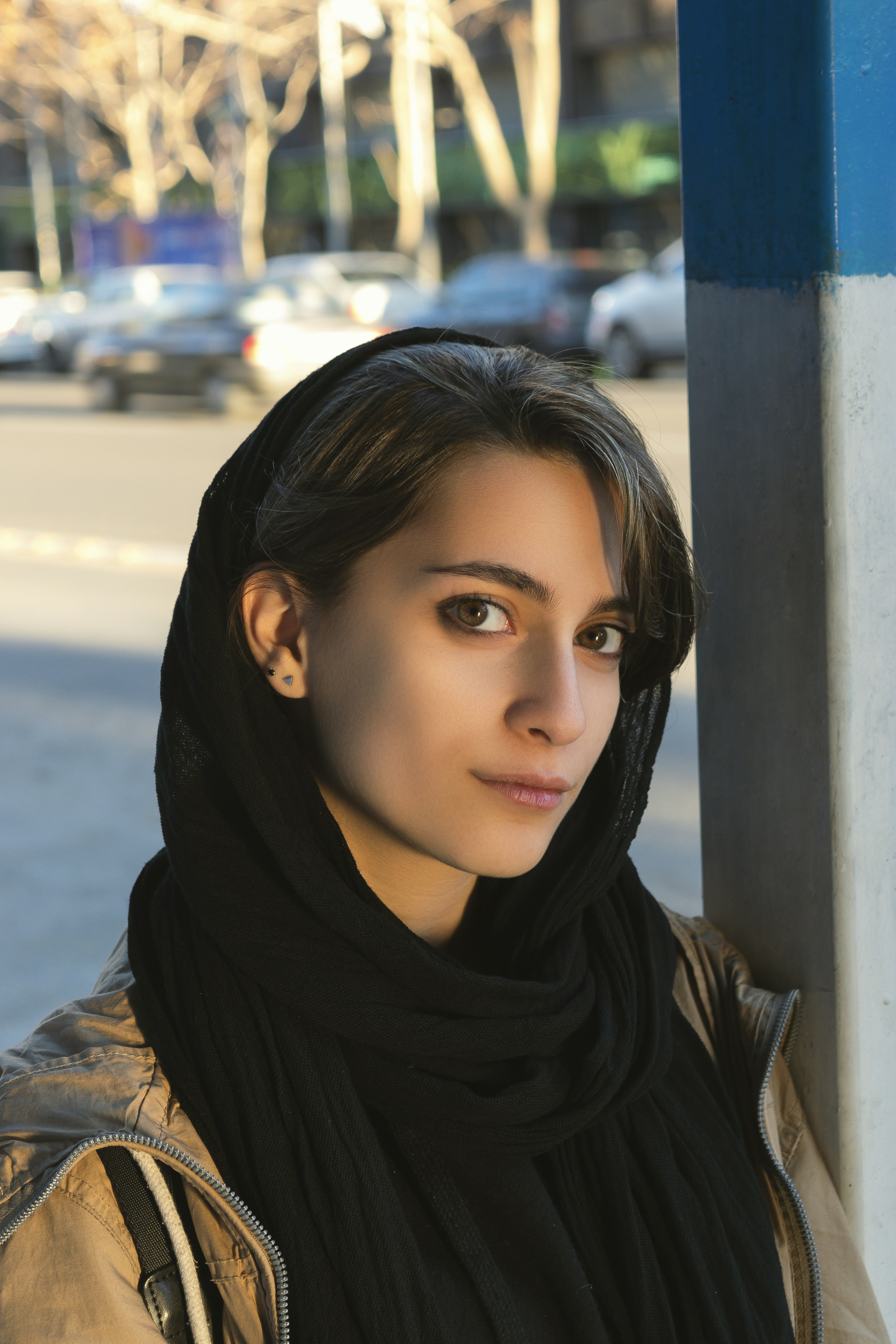 Una mujer apoyada en un poste en una calle de la ciudad