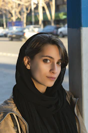 A woman leaning against a pole on a city street