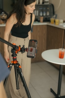 A woman standing next to a camera in a kitchen